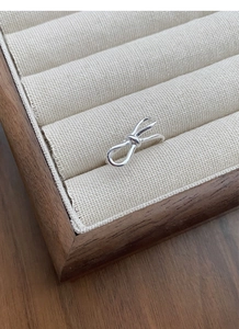 Close-up of S925 sterling silver bow ring displayed in a wooden jewelry box