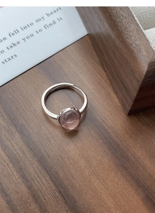 Detailed close-up of S925 sterling silver ring with oval pink gemstone on walnut wood