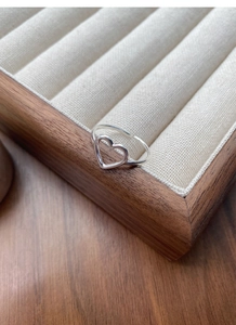 Detailed view of an S925 sterling silver hollow heart ring on a wooden jewelry display