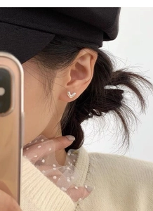 Close-up of minimalist S925 sterling silver heart studs worn by a model in a stylish setting