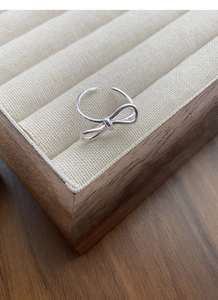 Polished S925 sterling silver bow ring with adjustable open band on jewelry display
