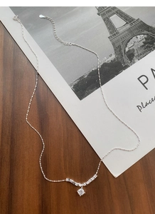 Detailed shot of S925 sterling silver necklace with zircon pendant on vintage wood