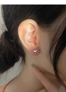 Detailed close-up of a minimalist S925 sterling silver heart stud earring on ear
