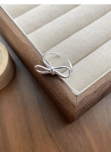 Detail view of S925 sterling silver bow ring displayed on a velvet jewelry organizer slot
