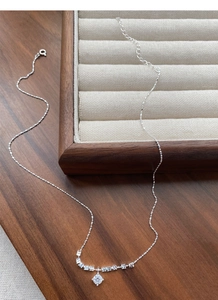 Close-up of S925 silver necklace with round zircon pendant and metallic beads on wood