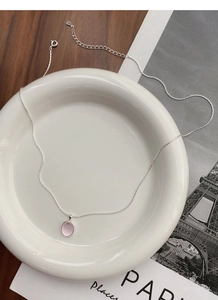 Detailed macro view of S925 sterling silver chain and pink oval gemstone on ceramic plate