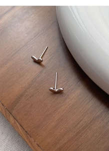 Close-up of minimalist S925 sterling silver heart-shaped stud earrings on wood surface