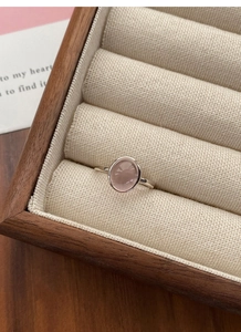 Pink oval rose quartz ring in S925 sterling silver set on a warm beige jewelry box liner