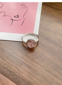 Detail of S925 sterling silver ring with oval pink stone on dark wood background