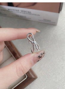 Detail of a minimalist S925 sterling silver bow ring with polished adjustable band