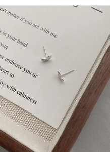 Macro detail of polished S925 sterling silver heart studs on a decorative white gift card