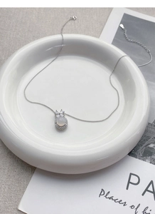 Macro shot of S925 silver necklace with chalcedony pendant and cubic zirconia bow detail