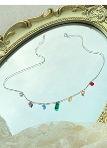Detail of colorful rainbow zircon necklace on a mirror with vintage gold frame