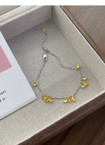 Macro shot of S925 silver slider bracelet with yellow teardrop zircon on a wooden tray