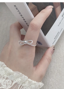 Close-up of S925 sterling silver bow ring on finger with elegant lace sleeve detail