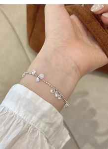 Detailed close-up of S925 sterling silver chain bracelet with yellow zircon on female wrist