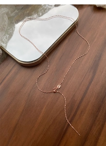 Detail of adjustable rose gold Y-necklace with sliding clasp and faceted link chain