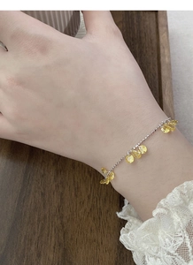 Detail of silver chain bracelet with teardrop yellow zircons worn on a female wrist