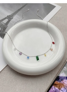 Detail of S925 silver beaded necklace with seven colorful geometric gemstones on ceramic