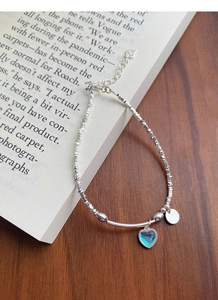 Details des Silberperlenarmbands mit herzförmigem Mondstein auf einem alten Buch