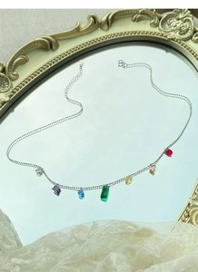 Macro shot of S925 silver rainbow gemstone necklace on a vintage mirror surface
