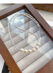 Macro shot of S925 silver beaded necklace with six lustrous pearls on velvet display