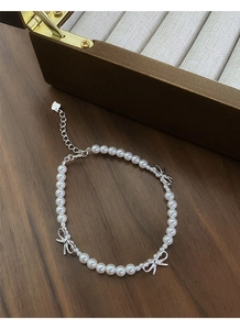 Détail du charme de nœud en argent S925 et des perles lustrées sur un bracelet bijoux