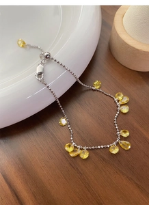 Detail of adjustable S925 silver bracelet with yellow zircon drops on ceramic dish