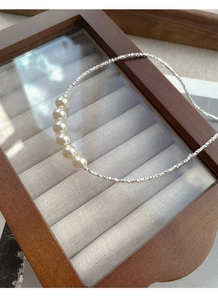 Detail of S925 silver necklace featuring seven elegant white pearls on a textured chain