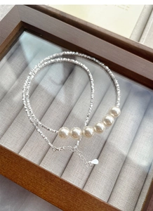Detail of silver beaded necklace with six lustrous pearls in a wooden jewelry box