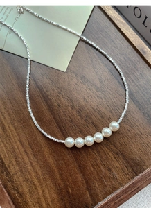 Detail of six 6mm pearls and faceted silver chain on dark walnut wood tray