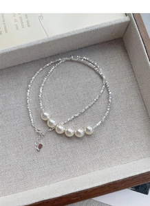 Detailed view of S925 sterling silver necklace with six elegant white pearls on a tray