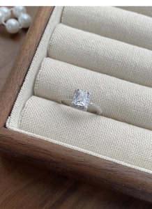 Detail shot of a sparkling geometric square zircon ring on a premium linen display