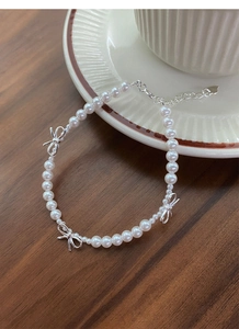 Vue détaillée d'un bracelet en perles et nœud en argent S925 sur une surface en bois