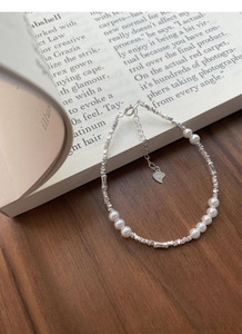 Detail of S925 silver pearl bracelet with heart charm on a vintage book background