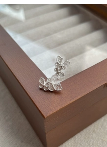 Macro detail of S925 sterling silver butterfly studs featuring intricate filigree design