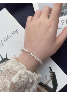 Détail de nœuds en argent S925 sur un bracelet délicat de perles blanches pour femmes