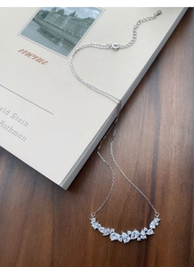 Macro shot of S925 silver wisteria smile necklace with pear-cut zircon on book backdrop