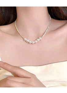 Detail of silver twisted chain necklace with seven glossy white pearls worn by a model