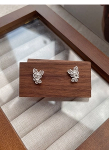 Detailed macro view of S925 silver butterfly studs with intricate filigree hollow pattern