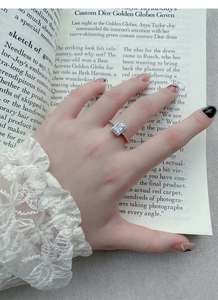Close-up of a geometric silver ring with sparkling square zircon on a lace background