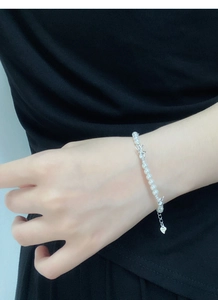 Détail du bracelet perles en argent S925 avec nœud papillon et breloque cœur au poignet