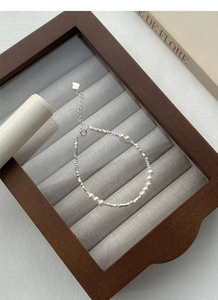 Detail of S925 silver beaded bracelet with white pearls and a small heart pendant