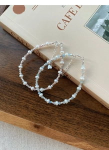 Macro detail of S925 sterling silver stamp on pearl and aquamarine beaded bracelet
