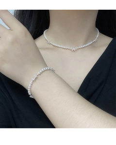 Gros plan d'un bracelet et collier en perles avec nœud en argent S925 sur modèle