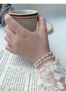 Detail of layered S925 silver bracelet with freshwater pearls and blue gemstones
