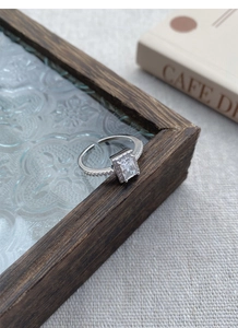 Macro shot of silver ring with large rectangular emerald-cut zircon and halo setting
