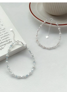 Detail of S925 silver bracelets with freshwater pearls and blue gemstones on white background