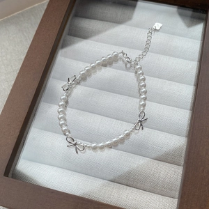 Bracelet en perles et argent S925 avec nœuds élégants sur un plateau à bijoux blanc