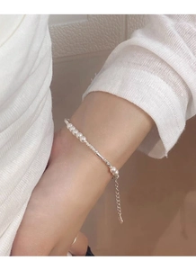 Detail of S925 silver pearl bracelet with adjustable chain and tiny heart charm on wrist